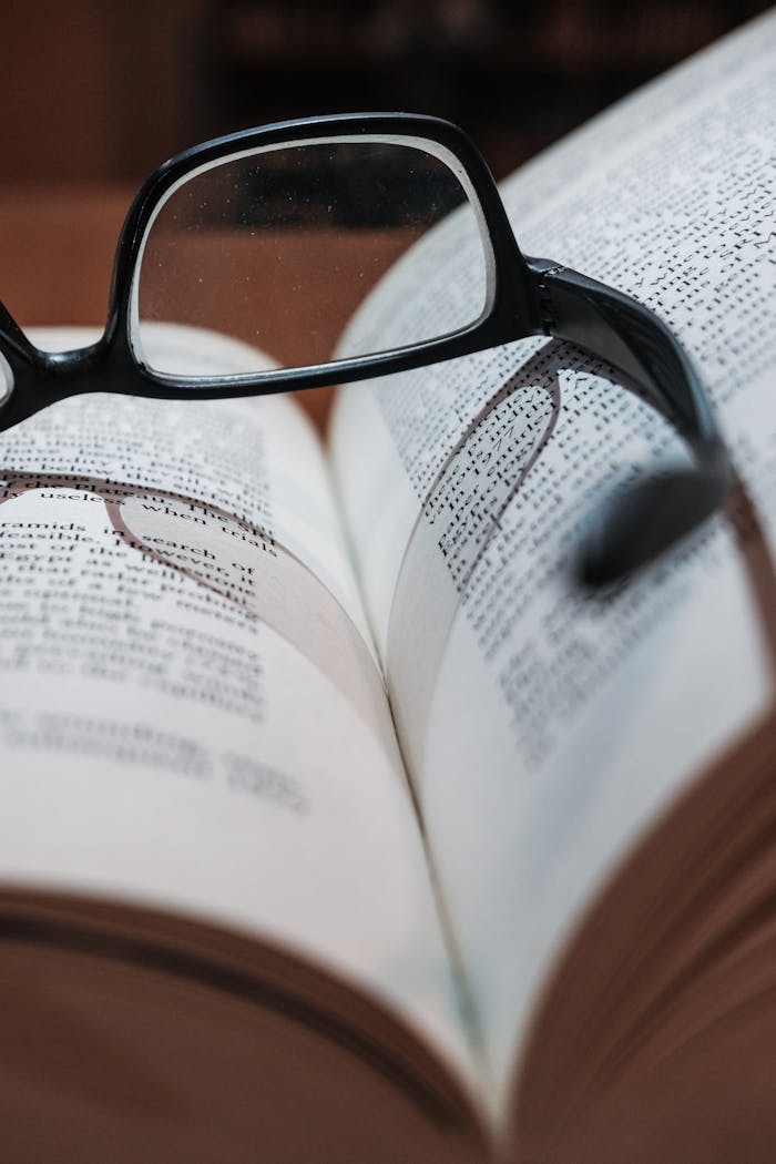 services-01 Eyeglasses resting on an open book, highlighting focus and depth of field.
